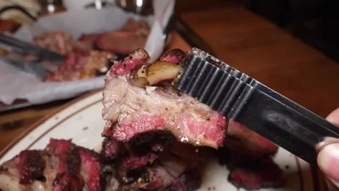Close-up of slow-smoked Texas-style beef brisket being served with metal tongs o Stock Footage 338212833