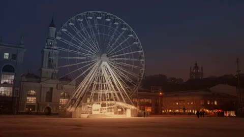 Close up of slowly moving ferris wheel at empty city square, tower, evening sky Stock Footage 268821628