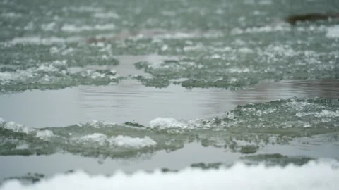 Close of slushy river flowing past iced river bank Stock Footage 327693578