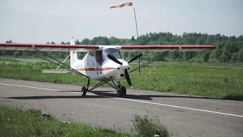 Close up of small airplane Rides on the runway, the girl pilot waves and smiles Stock Footage 76630876