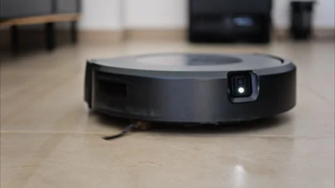 Close up of a small, black robot vacuum cleaning the house Stock Footage 305914191