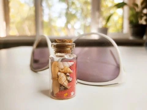 Close-up of a small bottle on a white background with red sand, seashells Stock Photos