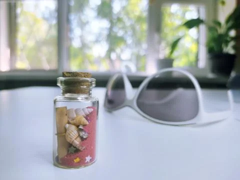 Close-up of a small bottle on a white background with red sand, seashells Stock Photos