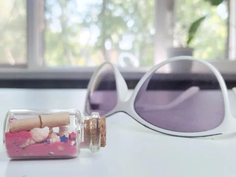 Close-up of a small bottle on a white background with red sand, seashells Stock Photos