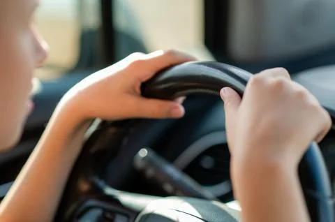 Close up of small childrens hands holding the steering wheel of a car symbo.. Stock Photos