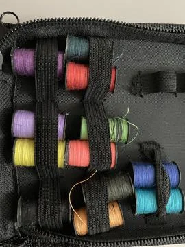 Close up Small color full spool of threat on the table with black zipper bag Stock Photos
