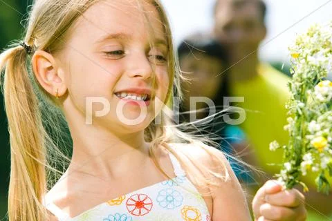Close-up of small cute girl with wildflowers in hand on the background of her pa Stock Photos
