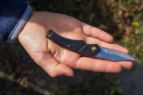 Close-up of a small folding knife held in a hand. Compact everyday tool with  Фото