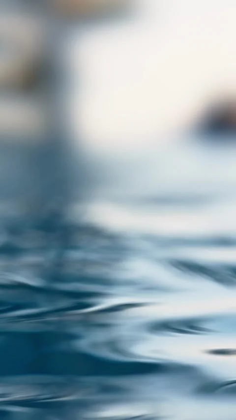 Close-up of small, gentle ripples on the surface of blue water with a blurred ba Stock Footage 314392869