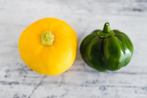 Close up of small green bell pepper and squash on wooden surface, simple ingr Stock Photos