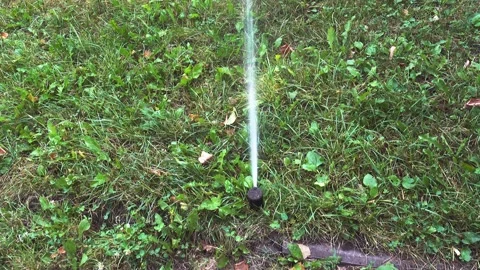 A close-up of a small ground sprinkler spraying a stream of water upwards Video stock 342037001