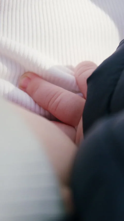 Close-up of small hand gently resting on soft fabric, showcasing warmth and Stock Footage 322178018