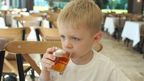 Close-up of a small happy boy having Breakfast in a restaurant, he drinks juice. Stock Footage 120106739
