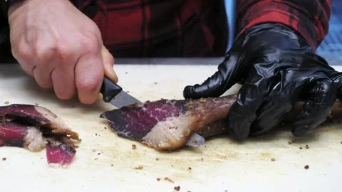 Close-up of small knife slicing through a strip of cured meat Stock Footage 342333479