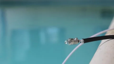 Close up of a small light bulb on a homemade wire with a pool in the background Stock Footage 345669826