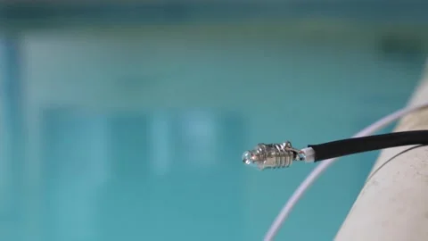 Close up of a small light bulb slowly turning on with a pool blurred in the Stock Footage 345669835