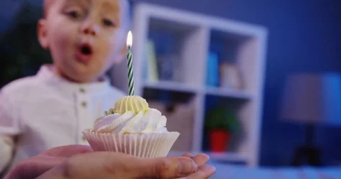 Close up of the small lovely boy blowing a candle on the little birthday cake in Stock Footage 82920463