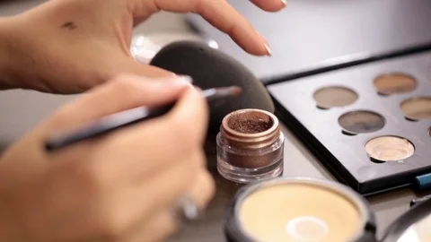 Close up of small makeup brush moving over brown eye shadows Stock Footage 86416420