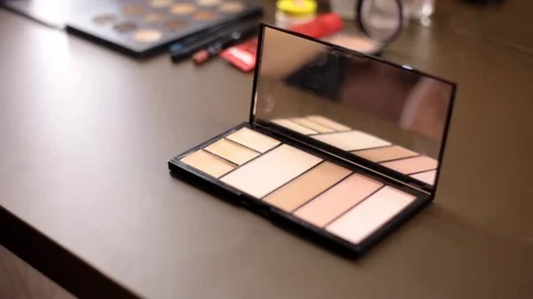 Close up of small makeup brush moving over brown eye shadows Stock Footage 86416432