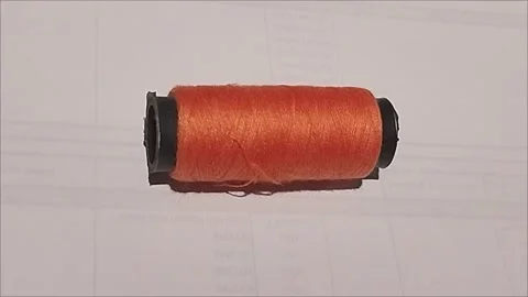 Close Up of Small Orange Sewing Thread Spool on White Background Stock Footage 296978478