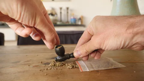 Close up of a small pipe being stuffed with marijuana. Video stock 344742648