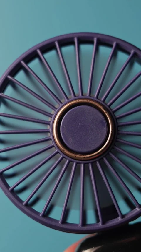 Close-up of a small, portable electric fan with a purple design Vidéo 343838048