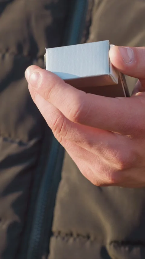 Close up of small rectangular object being rotated in hands against outdoor Stock Footage 345076774