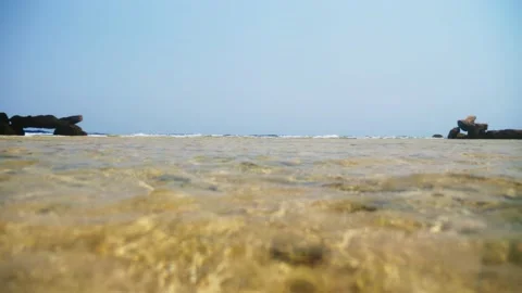 Close-up of small sea waves, clear sea water, yellow wet sandy and rocky bottom Stock Footage 136748617