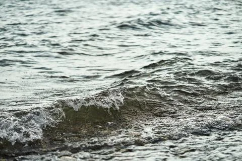 Close up of small sea waves moving over a rocky shoreline in Greece Stock Photos