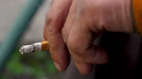 close-up of a small smoking half-smoked cigarette with a filter with a  marl