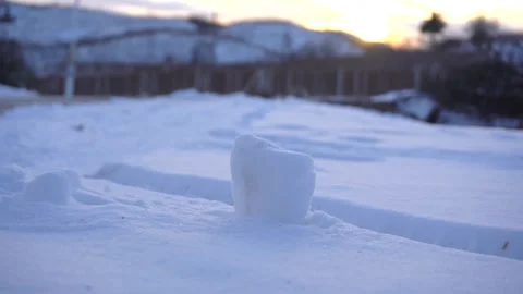 Close up of a small snowball sitting on a snowy ground at sunset Stock Footage 342212087