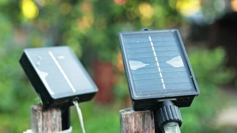 Close-up of small solar panels mounted on wooden stakes in a garden during .. Stock Footage 343532205