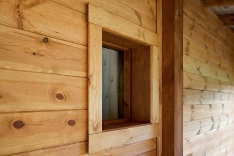 Close-up of small square glass window integrated into rustic wooden wall ma.. Stock Photos
