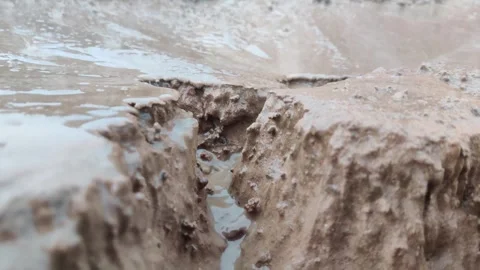 Close up of a small stream of water destroying the ground Stock-Footage 247734643