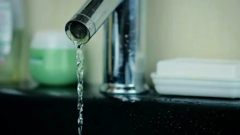 Close-up a small stream of water flowing from an aluminum tap in the bathroom. Stock Footage 81795433