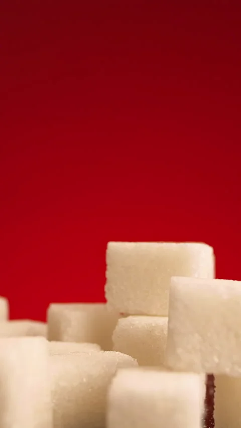 Close up of small sugar cubes falling down isolated on red background. Stock Stock Footage 289466180