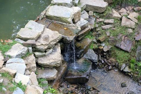 Close up of a small waterfall spilling over moss covered rocks in regional park Fotos de archivo