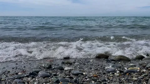 Close-up of small waves of the Black Sea hitting the shore with dark pebbles Stock Footage 279952900