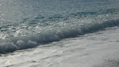 Close up small waves on shore of stone beach with city and mountains in Video stock 224052346