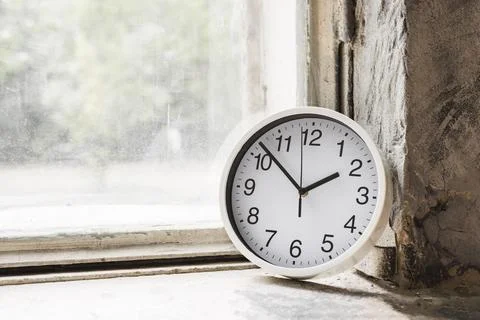Close up small white round clock near glass window 스톡 사진