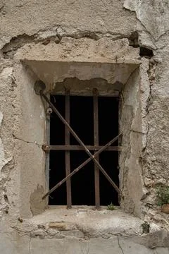 Close up of a small window with crossed rusty bars on a weathered stone wall Stock Photos