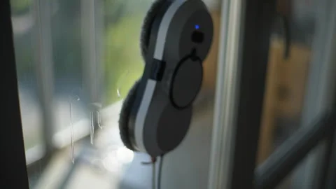 Close-up smart robot window cleaner washing dirty glass with round rags inside Stock Footage 251045932