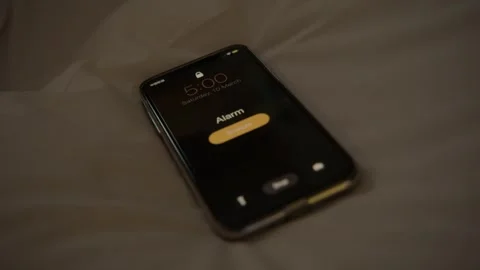 Close-Up of Smartphone Alarm Ringing on Bed in Early Morning Low Light Stock Footage 345681718