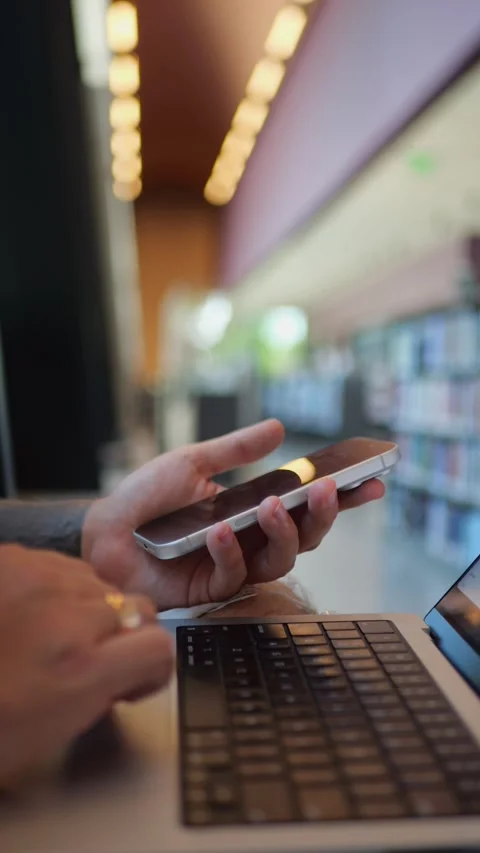 Close-Up of Smartphone and Laptop in Library Setting, Showing... 動画素材 334437358