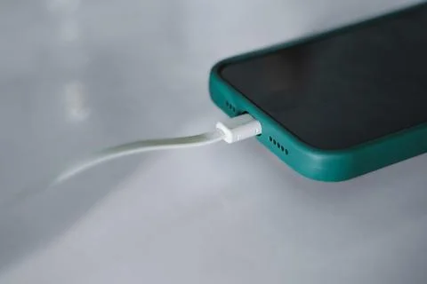 Close-up of Smartphone Charging with White Cable in Green Case 스톡 사진