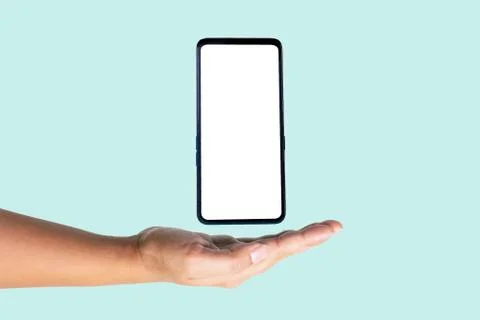 Close-up of a smartphone floating between the male's hand and a light blue ba Stock Photos
