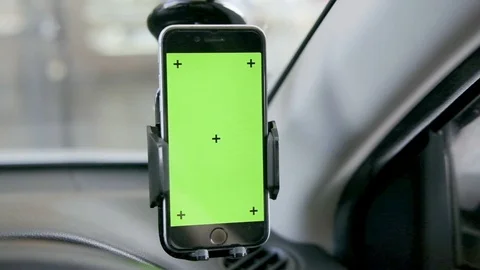 Close-up of smartphone with a green screen in the holder on windshield Stock Footage 116389377
