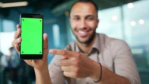 Close up of smartphone with green screen showing young businessman sitting  Stock Footage 255972848