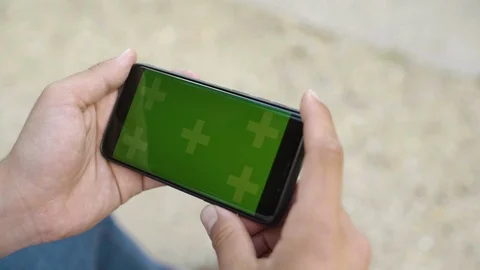 Close-up of smartphone with Green Screen Sitting on bench, holding by Video stock 111927235