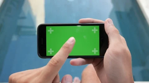 Close-up of smartphone with Green Screen Sitting at home near pool , holding by Stock Footage 125989270